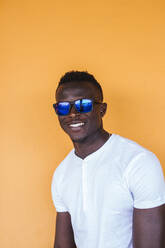 Portrait of smiling young man wearing white t-shirt and sunglasses - LJF00532