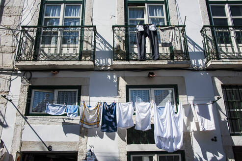 Niedriger Blickwinkel auf Kleidung, die vor dem Fenster einer Wohnung hängt, Lissabon, Portugal - RUNF02865