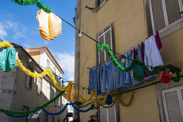 Niedriger Blickwinkel auf die an einer Wäscheleine hängende Dekoration eines Wohnhauses, Lissabon, Portugal - RUNF02872