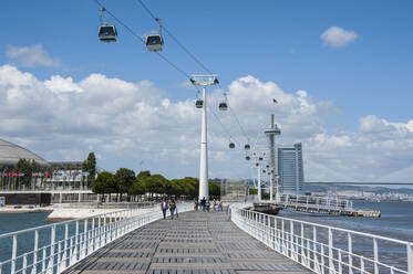 Menschen gehen auf der Brücke, die zum Vasco-da-Gama-Turm führt, über den Fluss in der Stadt gegen den Himmel, Lissabon, Portugal - RUNF02882