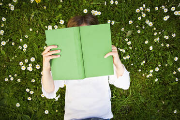 Mädchen liegt auf einer Wiese und liest ein Buch, von oben - LVF08224