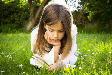 Girl lying on a meadow reading a book - LVF08225