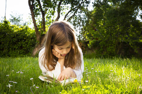 Girl lying on a meadow reading a book stock photo