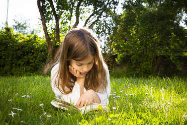Girl lying on a meadow reading a book - LVF08226