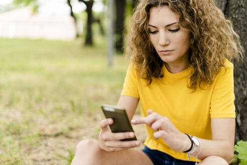 Junge Frau benutzt Mobiltelefon in einem Park - GIOF06987