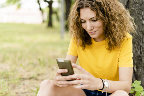 Junge Frau benutzt Mobiltelefon in einem Park - GIOF06988