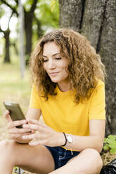 Young woman using cell phone in a park - GIOF06989