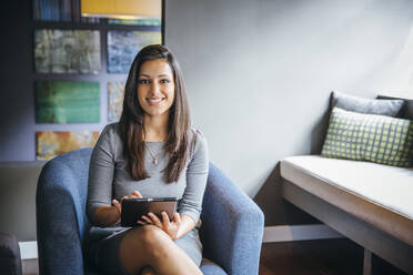 Mixed race businesswoman using digital tablet in office lobby - BLEF12333