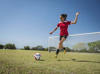 Mixed race soccer player kicking ball on field - BLEF12357
