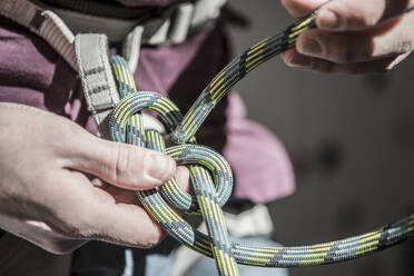 Sportler beim Binden eines Knotens am Klettergurt - BLEF12381