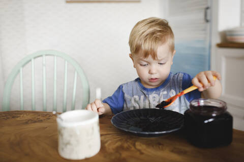 Süßer kleiner Junge isst Blaubeermarmelade, lizenzfreies Stockfoto