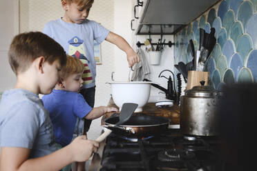 Three brothers cooking pancakes in the kitchen - EYAF00345