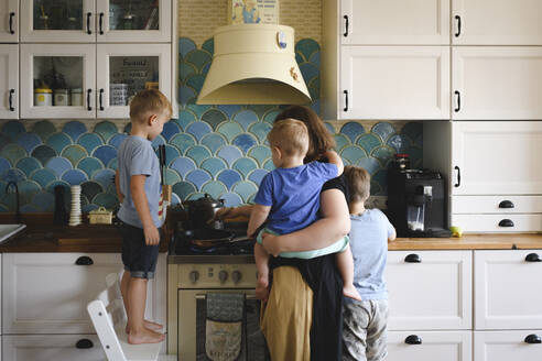 Mutter kocht mit ihren drei Söhnen in der Küche - EYAF00347