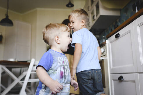 Zwei kleine Jungen rennen in der Küche - EYAF00349