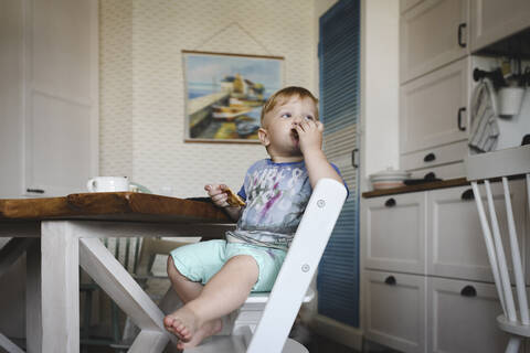 Kleiner Junge isst Pfannkuchen in der Küche, lizenzfreies Stockfoto