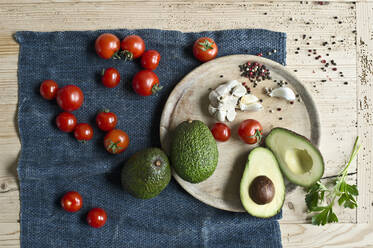Directly above shot of avocados with tomatoes and spices on wooden table - ASF06461