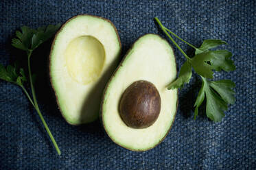 Directly above shot of halved avocado with parsley on dish towel - ASF06466