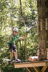 Kaukasischer Junge balanciert auf Slackline im Wald - BLEF12519