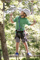 Caucasian boy balancing on slackline in forest - BLEF12520