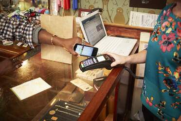 Frau benutzt Mobiltelefon zum Bezahlen im Geschäft - BLEF12533