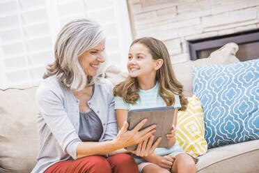 Caucasian grandmother and granddaughter using digital tablet on sofa - BLEF12550