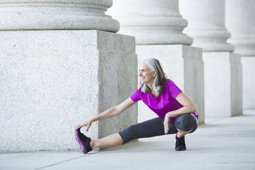 Caucasian woman stretching outside courthouse - BLEF12603