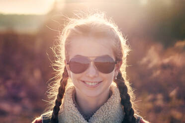 Kaukasisches Teenager-Mädchen mit Sonnenbrille auf einem Feld - BLEF12645