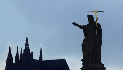 Silhouette einer Statue und eines Kruzifixes zwischen Kirchtürmen, Prag, Böhmen, Tschechische Republik, - BLEF12719