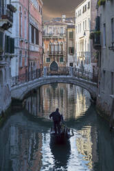Gondolier sailing on Venice canal, Veneto, Italy - BLEF12748