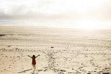 Caucasian girl standing with arms outstretched on beach - BLEF12761