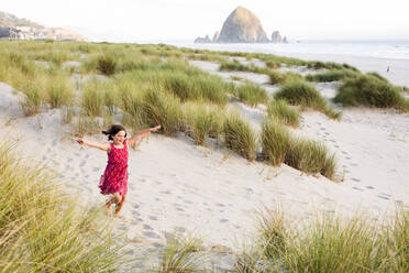 Caucasian girl running with arms outstretched on beach - BLEF12762