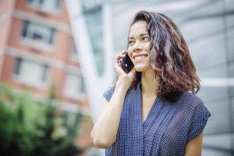 Gemischtrassige Geschäftsfrau, die im Freien mit einem Handy telefoniert, lizenzfreies Stockfoto