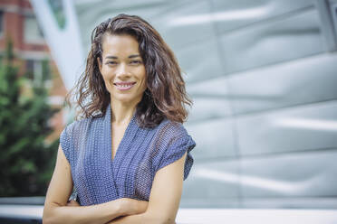 Mixed race businesswoman standing with arms crossed outdoors - BLEF12803