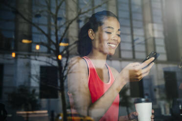 Mixed race woman using cell phone in cafe - BLEF12809