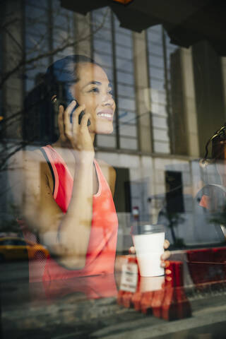 Gemischtrassige Frau, die in einem Café mit einem Handy telefoniert, lizenzfreies Stockfoto