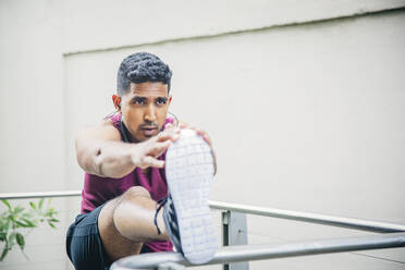 Indian man stretching on banister - BLEF12825