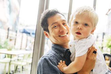 Smiling father holding son by window - BLEF12858