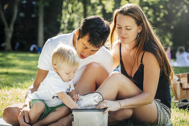 Familie öffnet Picknickbox im Park - BLEF12871