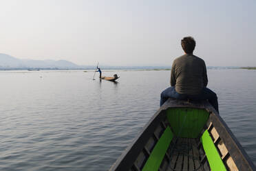 Caucasian man sitting on canoe on rural lake - BLEF12955