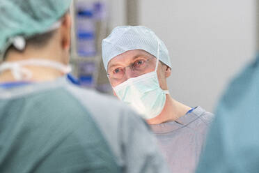 Chirurg während einer Operation, Blick zum Kollegen - MWEF00198