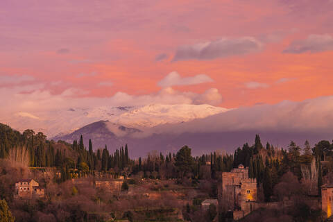 Blick auf die Alhambra mit dem Berg Sierra Nevada im Hintergrund bei Sonnenuntergang, Granada, Spanien, lizenzfreies Stockfoto