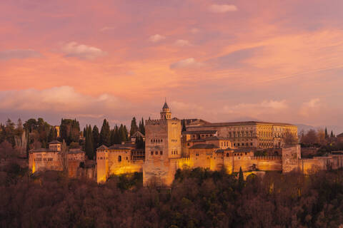 Blick auf die Alhambra mit dem Berg Sierra Nevada im Hintergrund bei Sonnenuntergang, Granada, Spanien, lizenzfreies Stockfoto