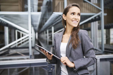 Smiling businesswoman using tablet in a factory - BSZF01172