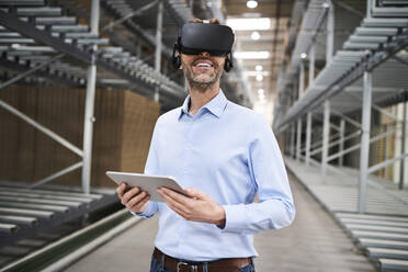 Geschäftsmann mit Tablet und VR-Brille in einer Fabrik - BSZF01191