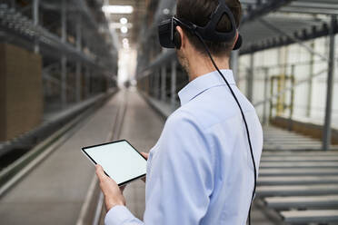 Geschäftsmann mit Tablet und VR-Brille in einer Fabrik - BSZF01193