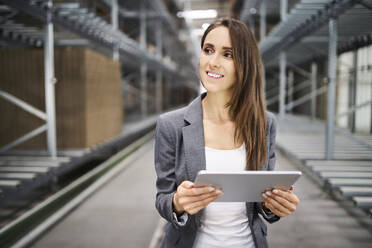Smiling businesswoman using tablet in a factory - BSZF01198