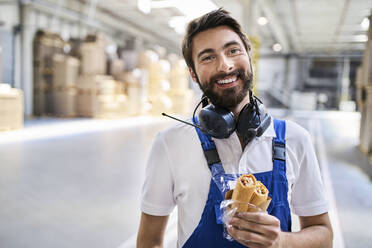 Glücklicher Arbeiter in der Mittagspause in einer Fabrik - BSZF01210