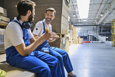 Zwei glückliche Arbeiter in der Mittagspause in einer Fabrik - BSZF01211