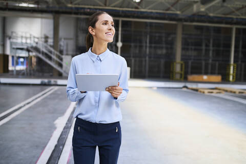 Lächelnde Geschäftsfrau mit Tablet in einer Fabrik, lizenzfreies Stockfoto