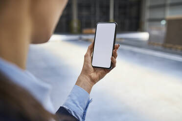 Close-up of businesswoman holding cell phone in factory - BSZF01231